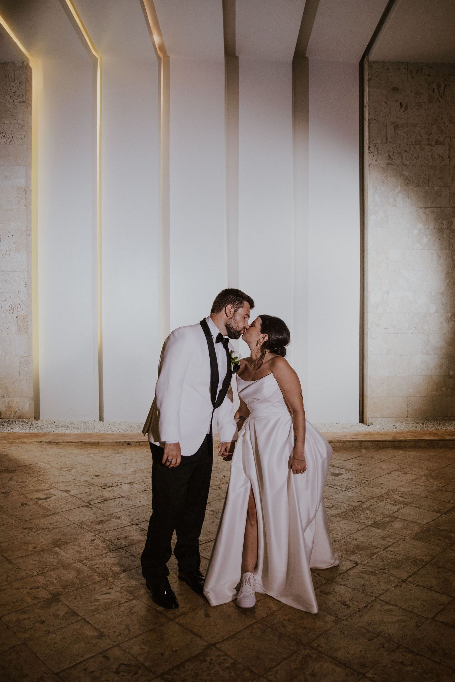 Romantic moment of couple sharing an intimate dance in front of illuminated geometric wall design.