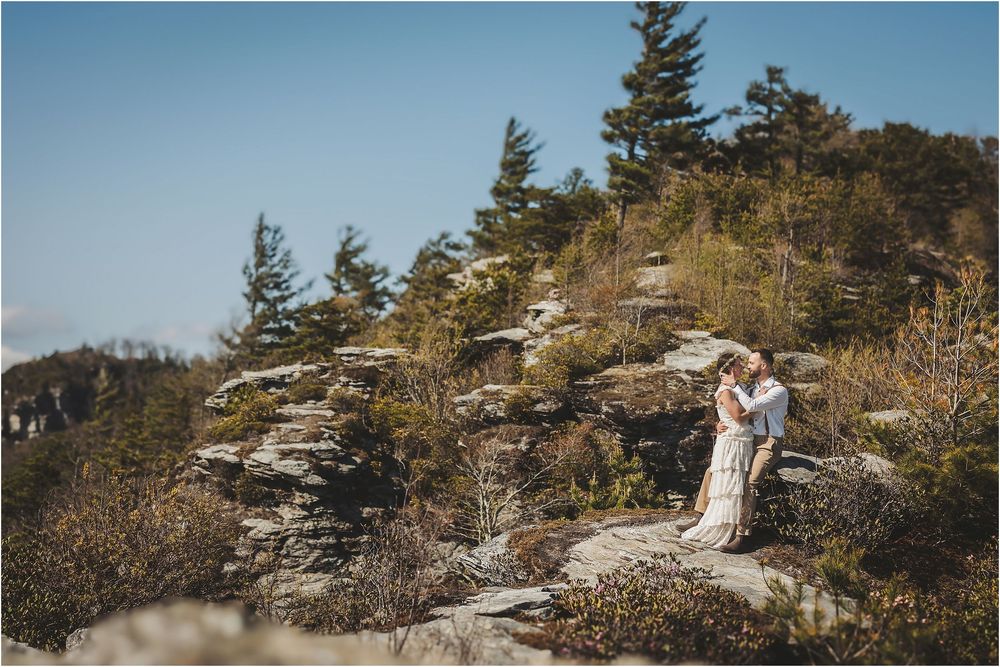 Mountain wedding ceremony on a scenic cliff edge overlooking a vast autumn landscape.