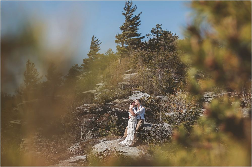 Panoramic mountain vista captures an intimate wedding moment on a rocky overlook.