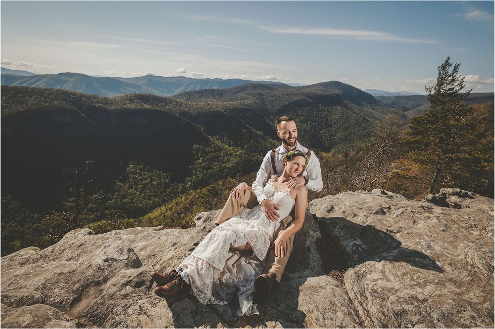 A sweet moment captured on a rocky cliff with mountains and valleys stretching into the distance.