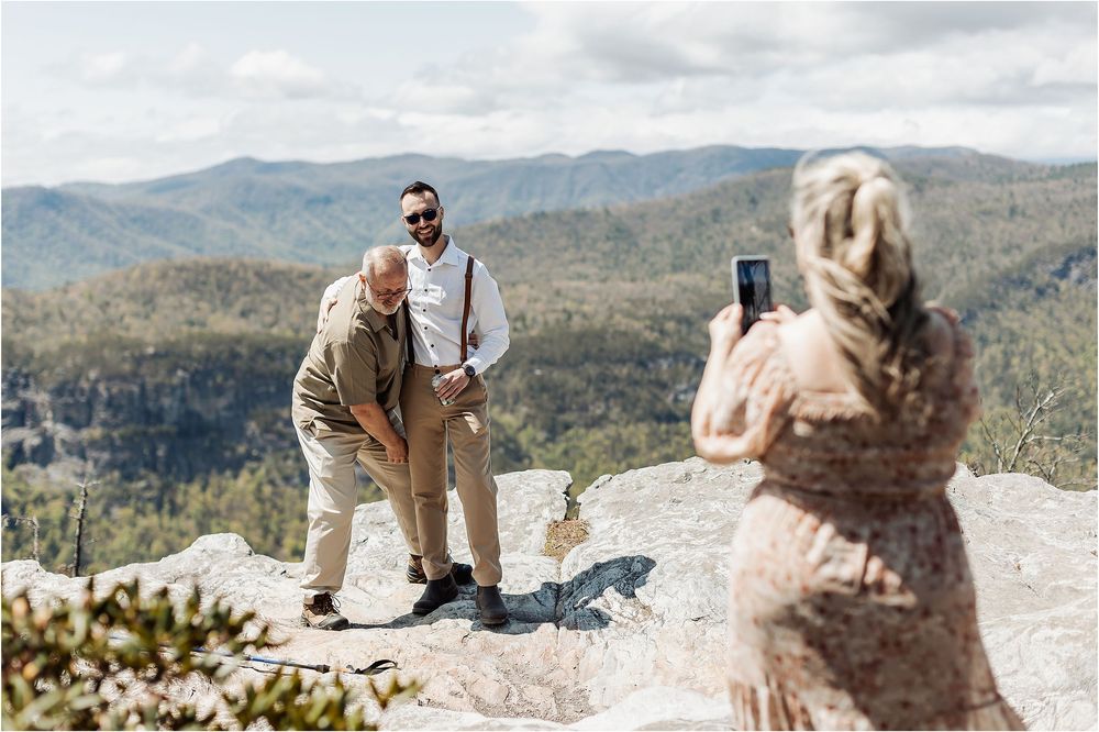 Someone taking photos during a mountain top ceremony with expansive valley views.