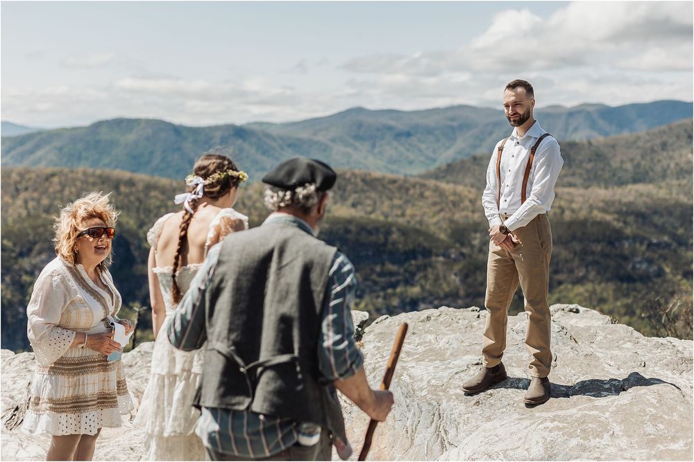 A mountain wedding ceremony in progress with dramatic landscape views in the background.