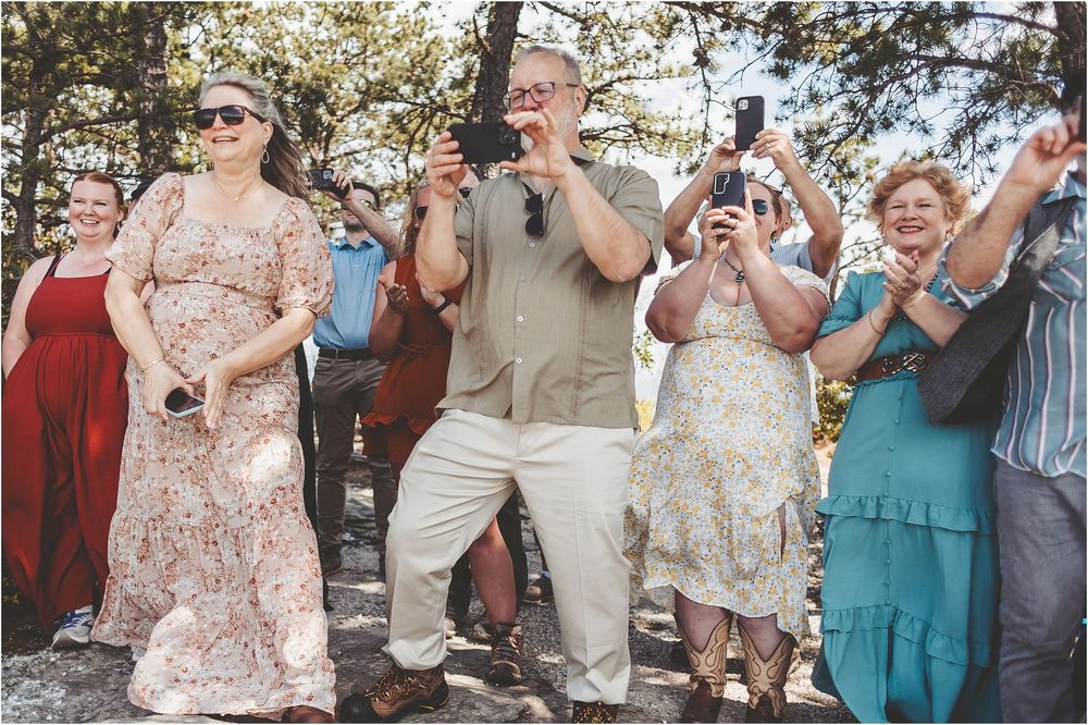Wedding guests celebrate joyfully outdoors during a mountain ceremony.