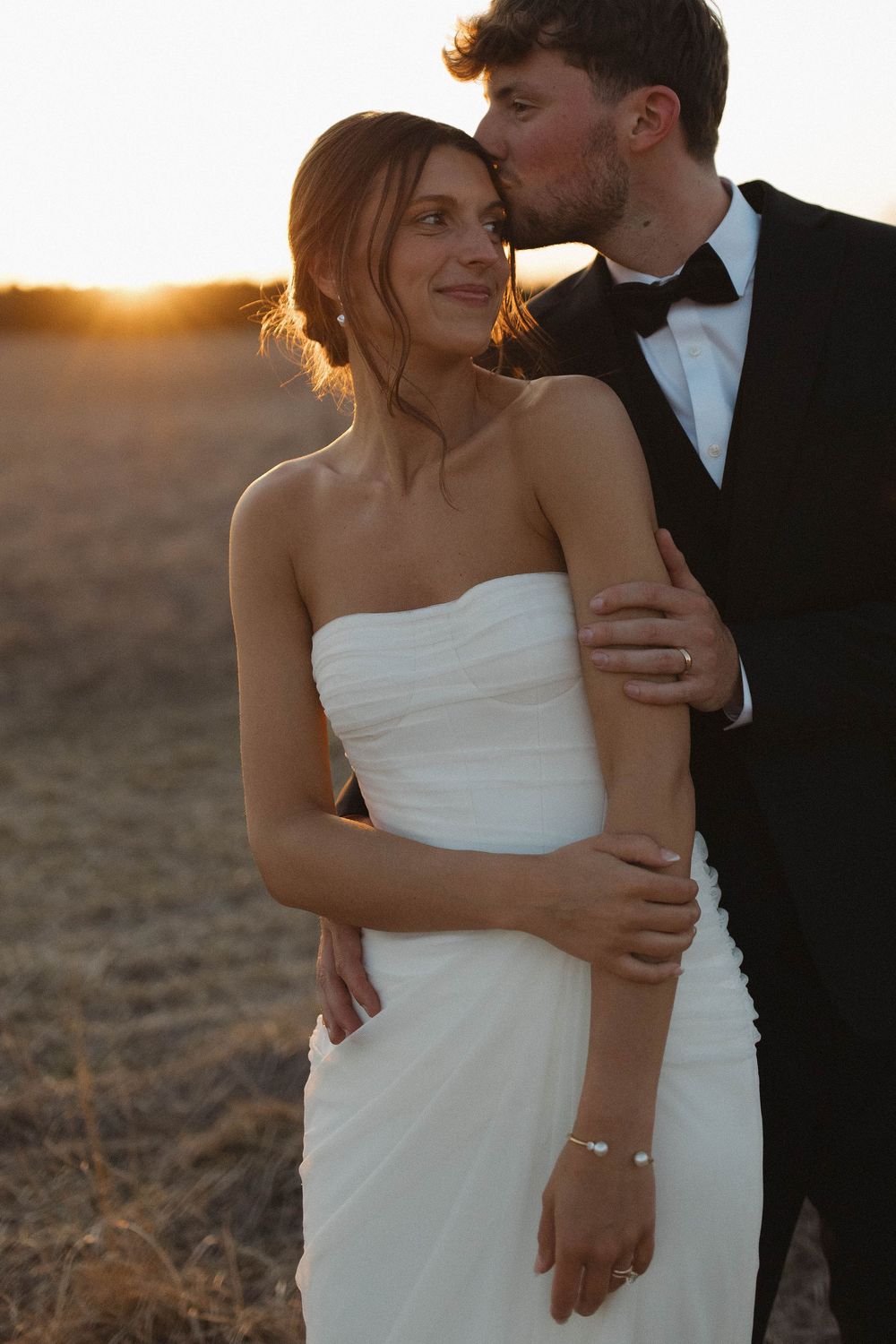Intimate wedding portrait of a couple in formal attire during golden hour.