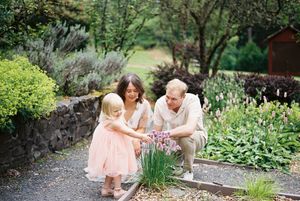 A family sharing tender moments together in a lush garden setting with blooming flowers and greenery.