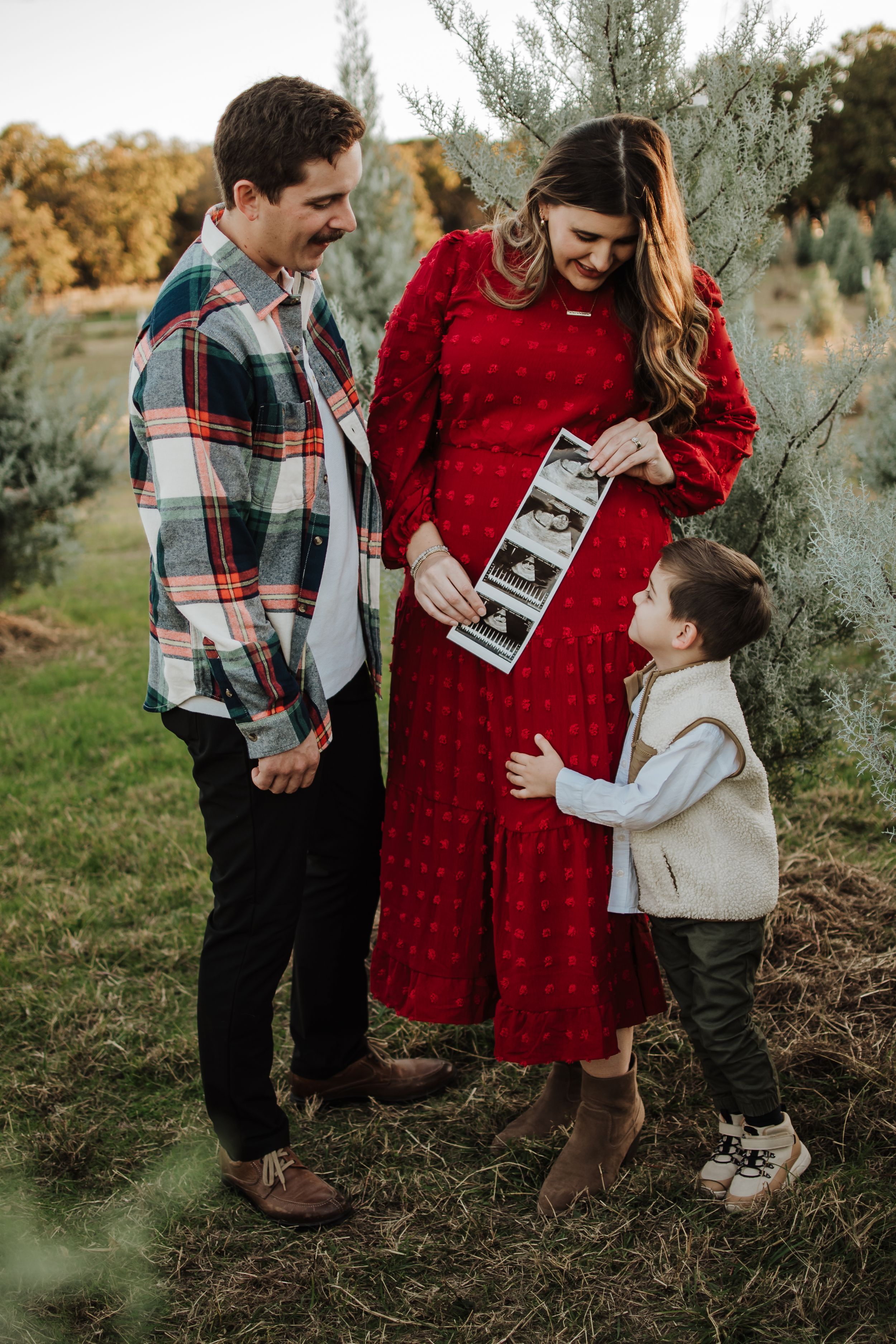 Family sharing a joyful moment while looking at ultrasound photos outdoors.