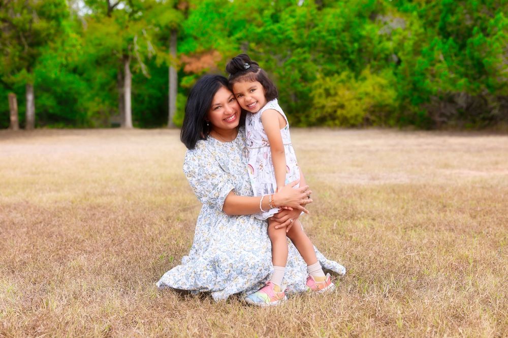 Family enjoying a picturesque summer day together on a golden grass field wearing white dresses.