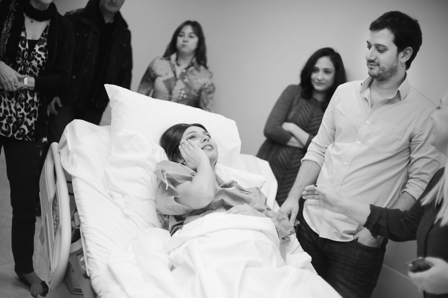 Black and white photo of several people gathered around a hospital bed in a medical room.