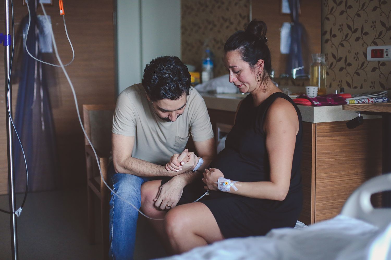 Two people share an intimate moment together in a hospital room while sitting close to each other.
