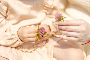 Close-up of hands gently pressing light pink clay dough in a therapeutic clay sculpting session.