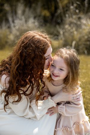 A heartwarming sequence of embraces and laughter between two people wearing light-colored clothing in a sunlit natural setting.