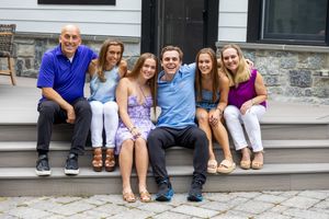 A group of six people sitting together and smiling on outdoor stone steps.