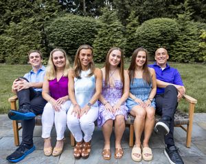 Friendship bench panorama shows a group wearing coordinated white outfits sitting together outdoors in a summer setting.