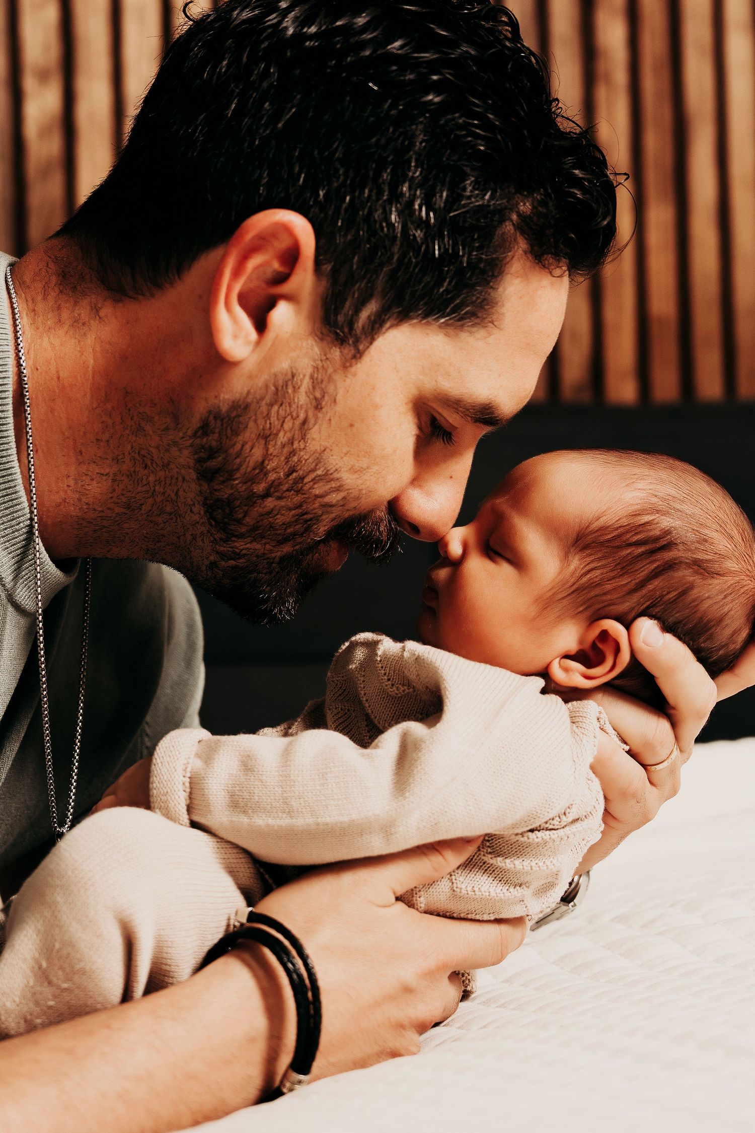 A tender moment between parent and baby in soft indoor lighting.