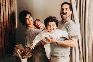 A joyful family shares a tender moment together in a warmly lit room with wooden paneling.
