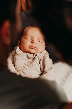 A peaceful sleeping newborn baby wearing a beige chevron patterned outfit.