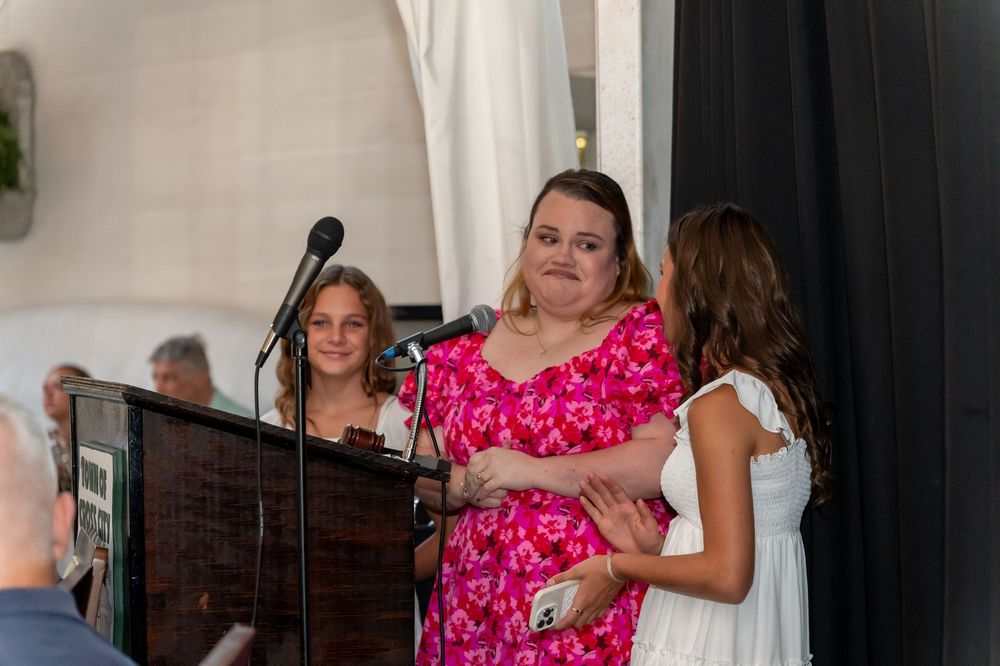 People gather around a microphone at an indoor event or celebration.