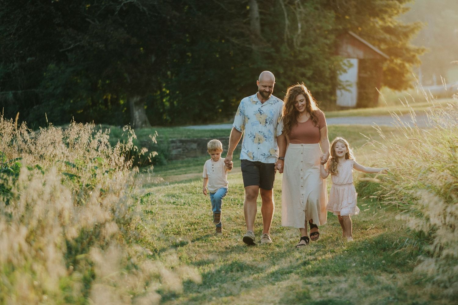 Family walking together through a sunlit meadow at golden hour during summer.