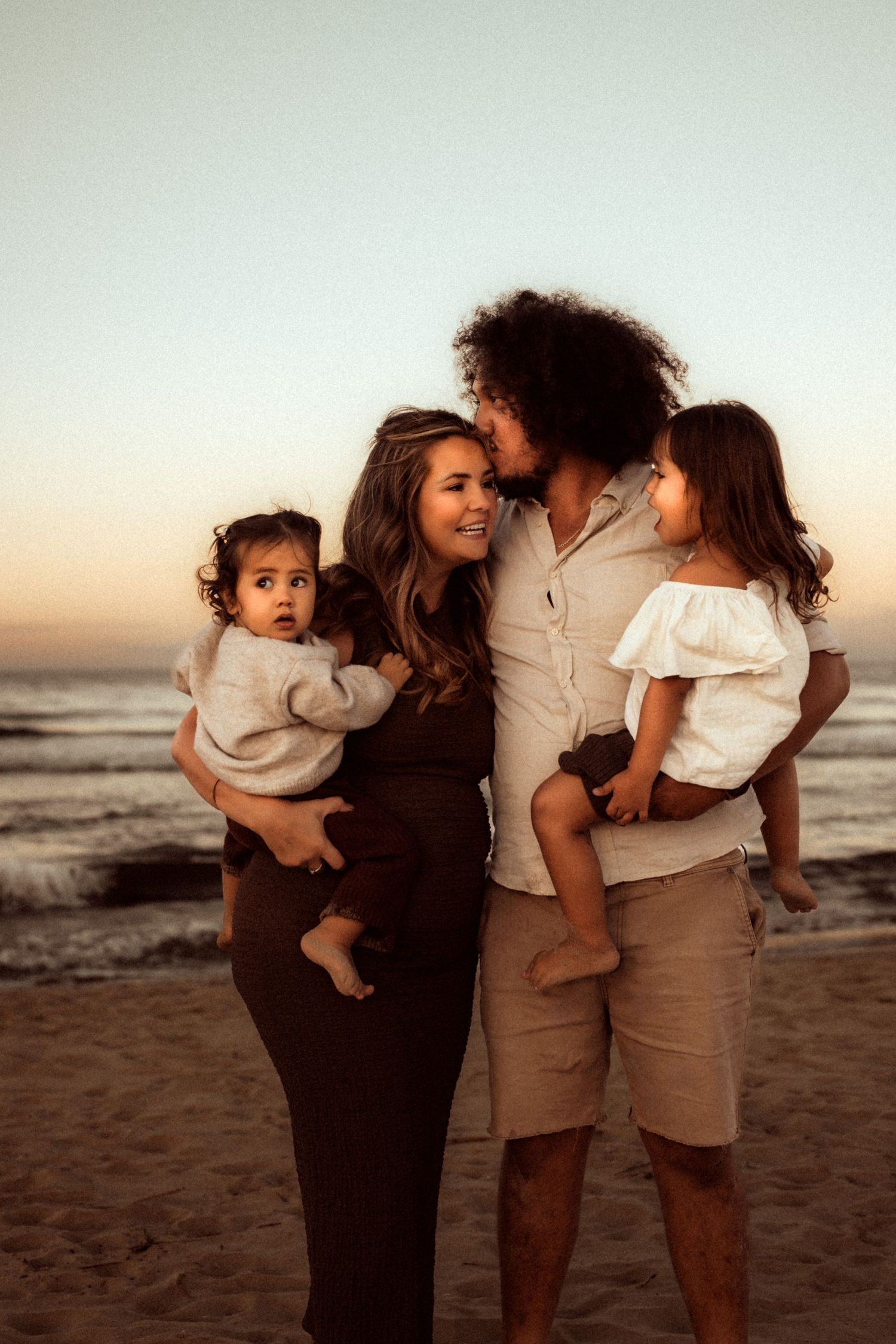 A family in Javea shares an intimate moment together on the beach at sunset. Javea family  photographer