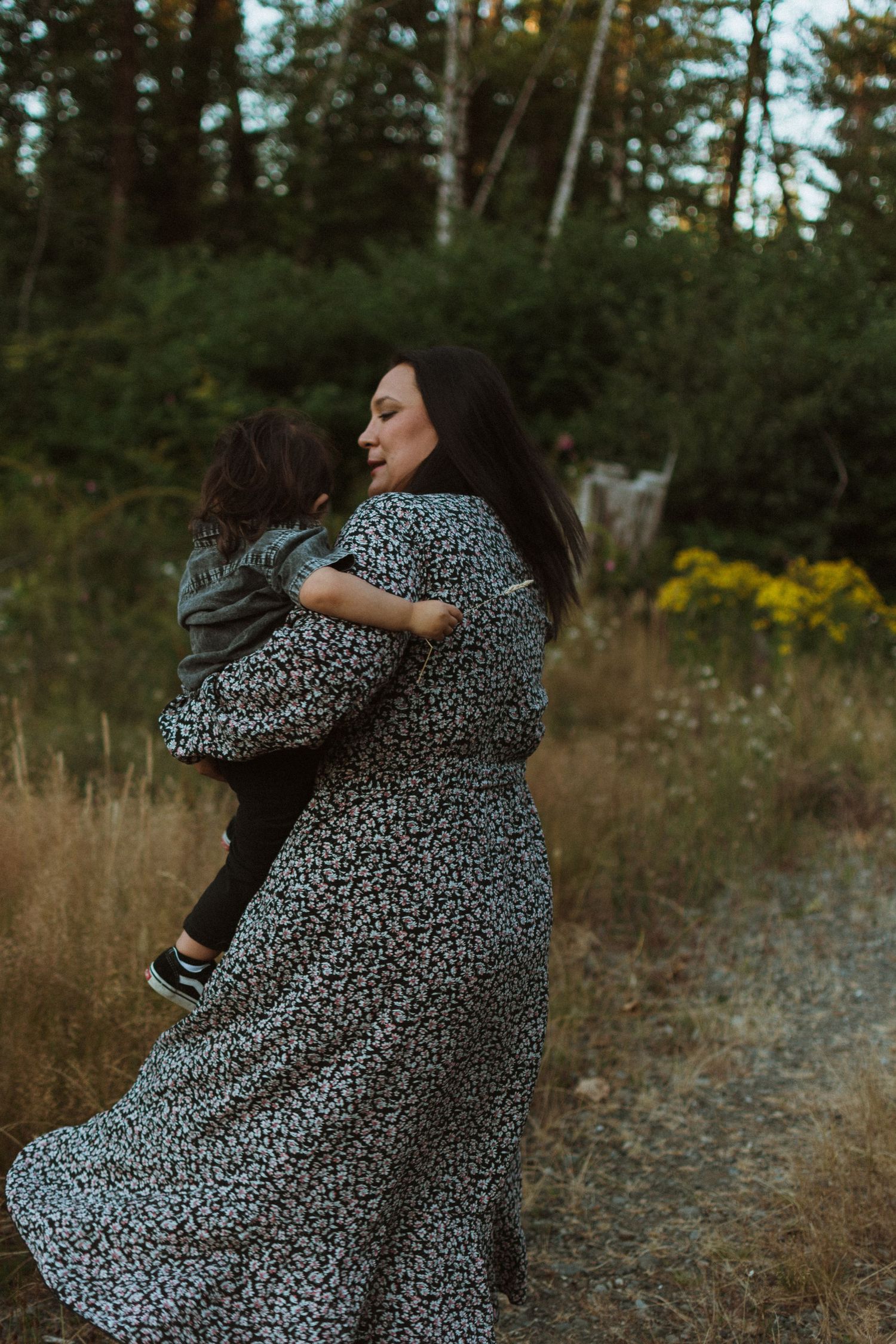 Mother spinner her toddler in a field