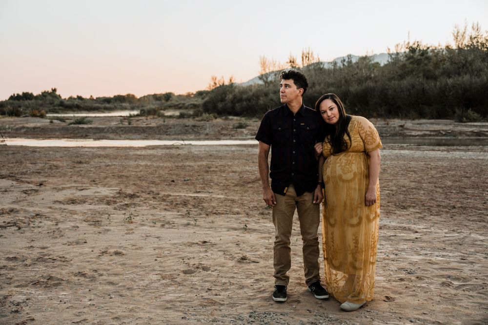 A couple shares a romantic moment in a desert landscape with hot air balloons visible.