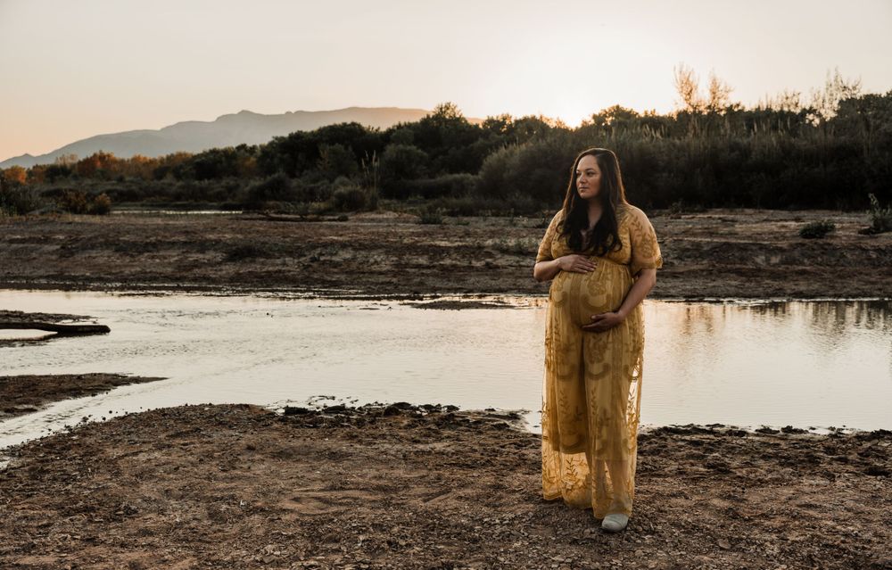 A romantic sunset photoshoot at a desert lake with a couple in casual attire and golden light.