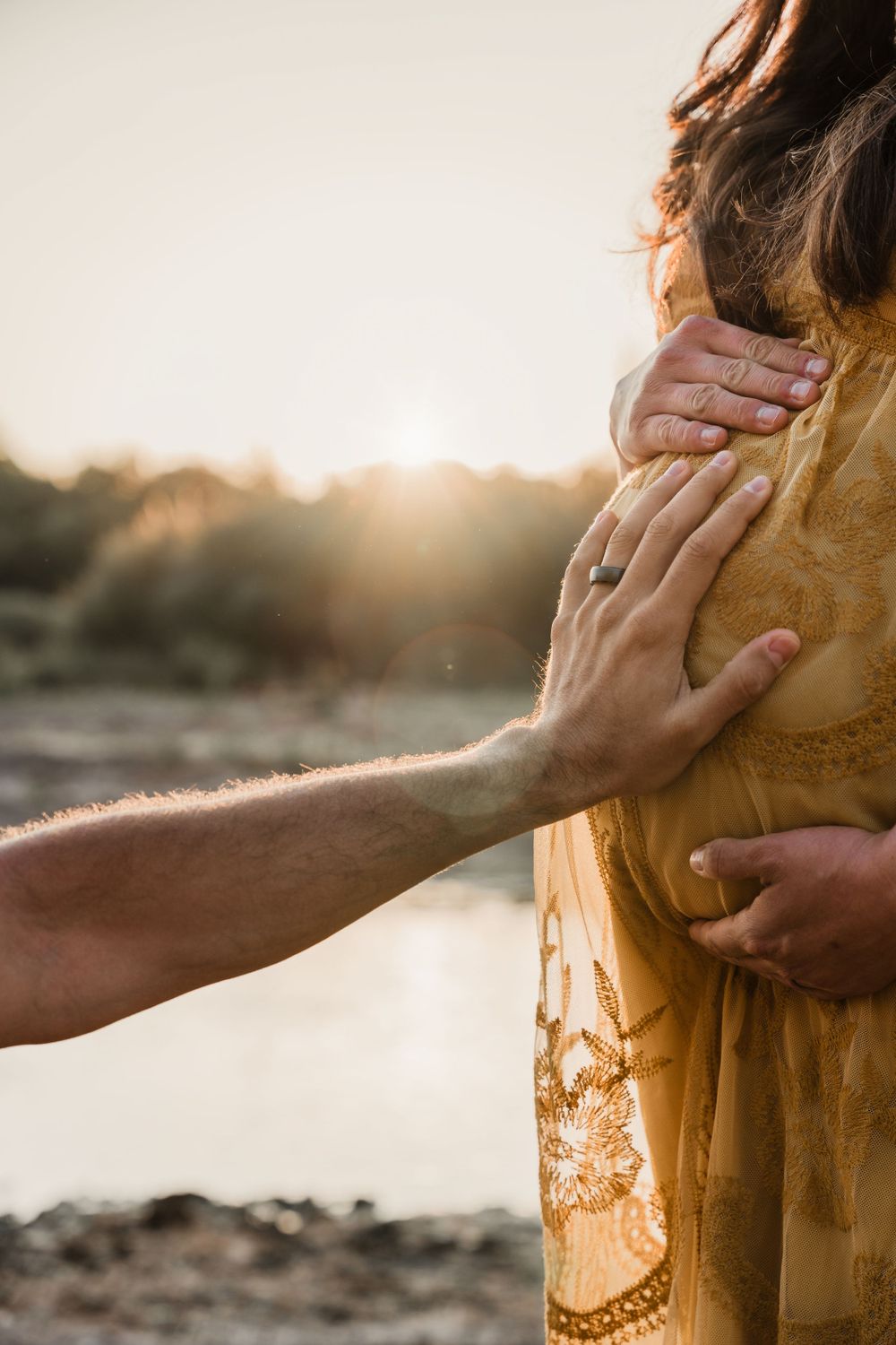 Closeup of gentle hands caressing during a sunset desert photoshoot.