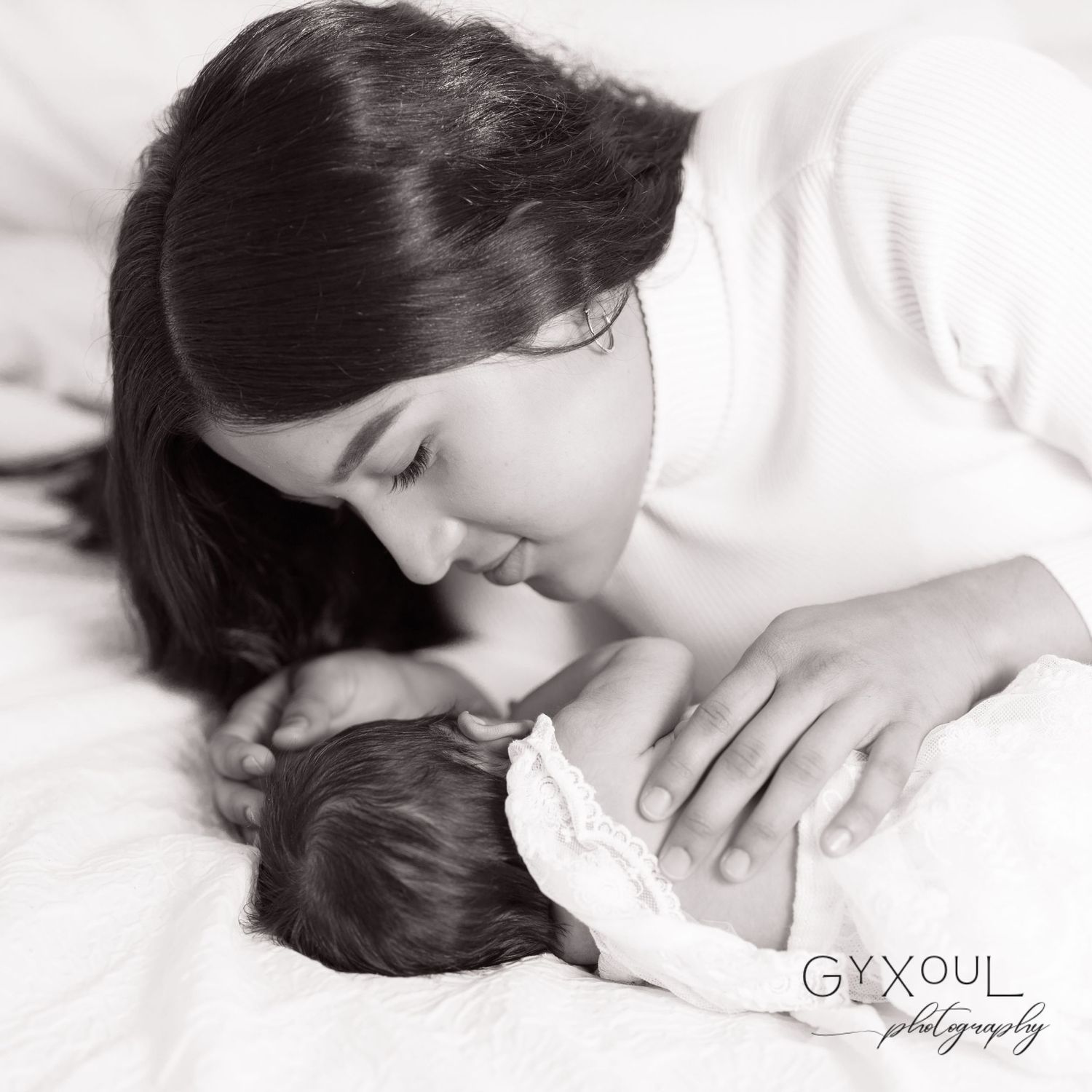 Intimate black and white portrait of mother and baby sharing tender moment.