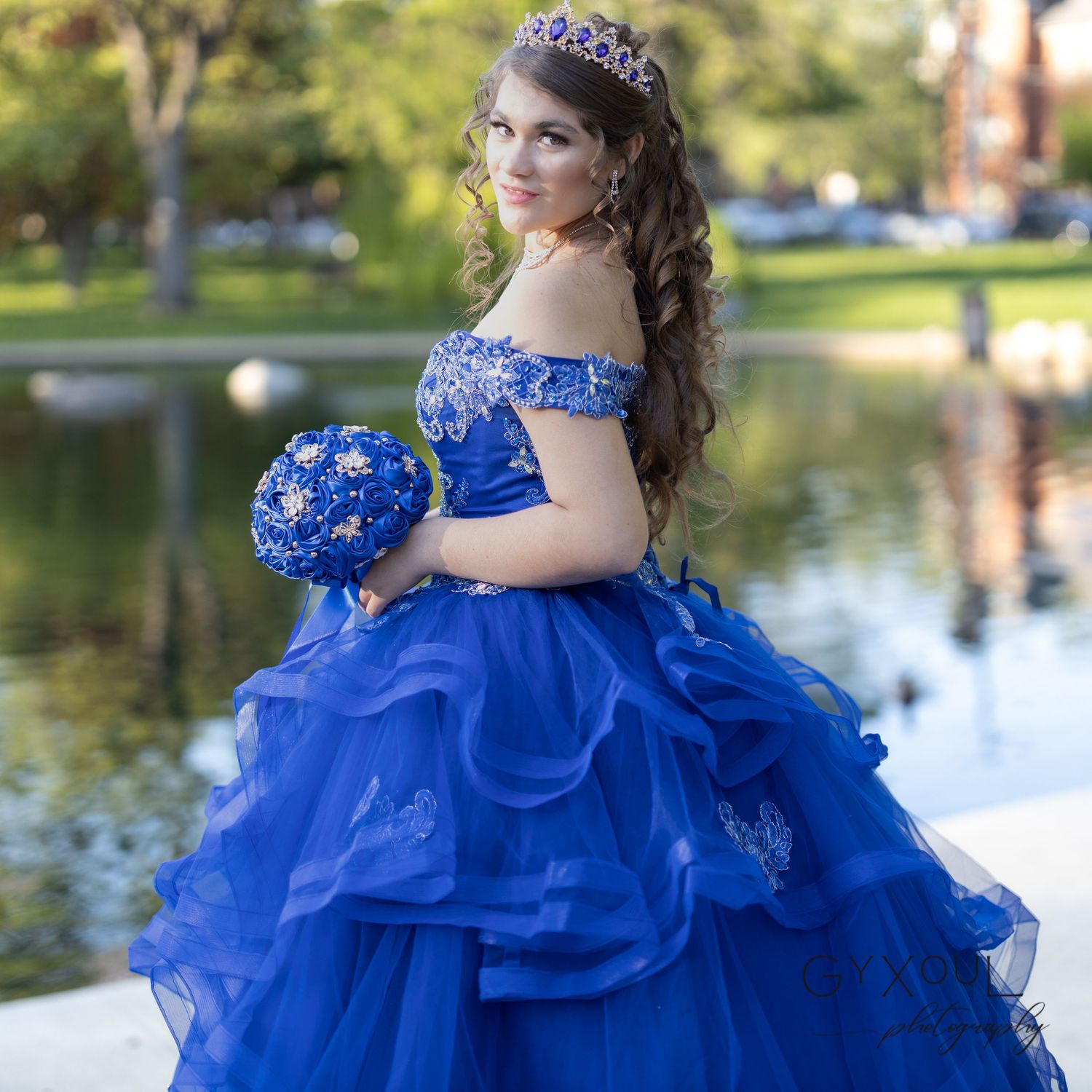 Stunning royal blue quinceañera dress with matching bouquet captured by lakeside reflection.
