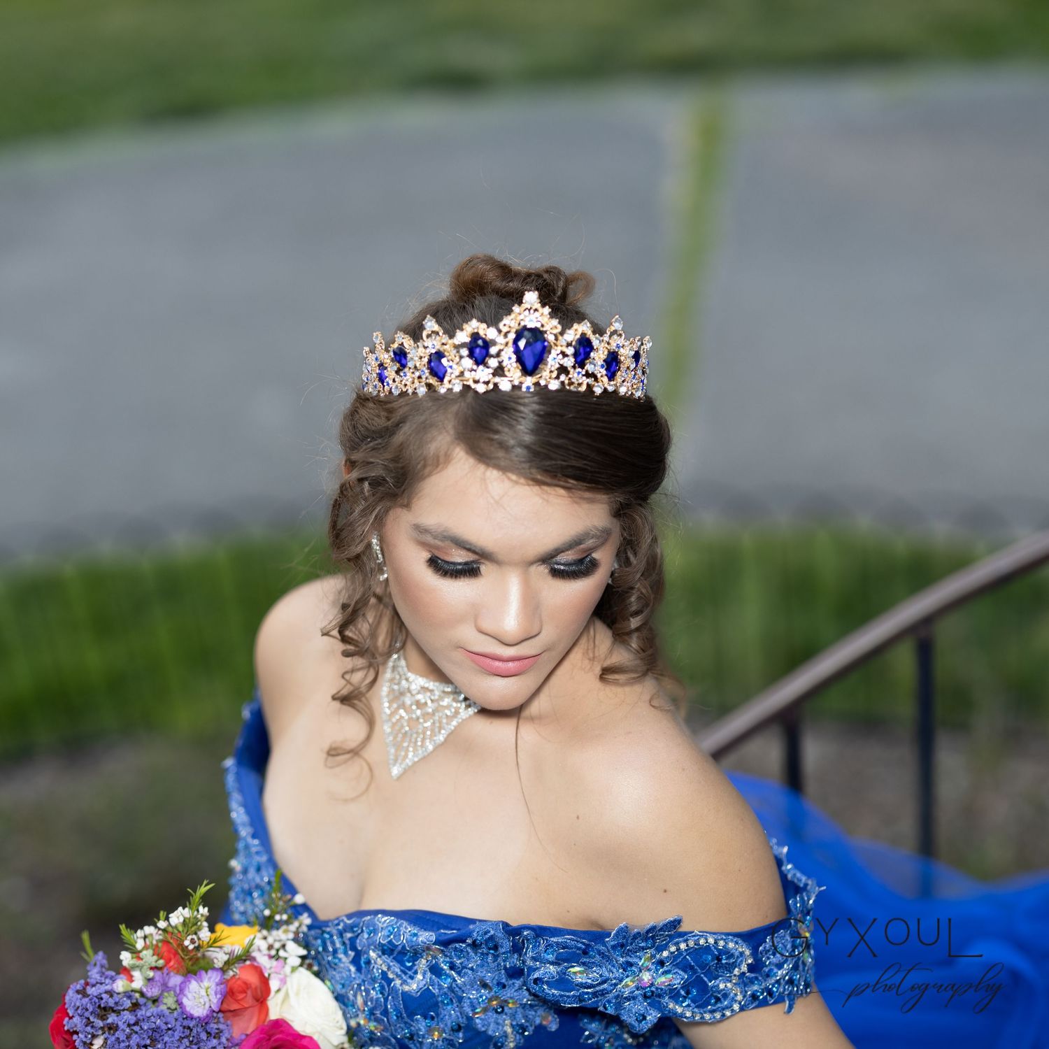 Detailed shot of sparkling tiara and jeweled necklace with royal blue dress bodice.