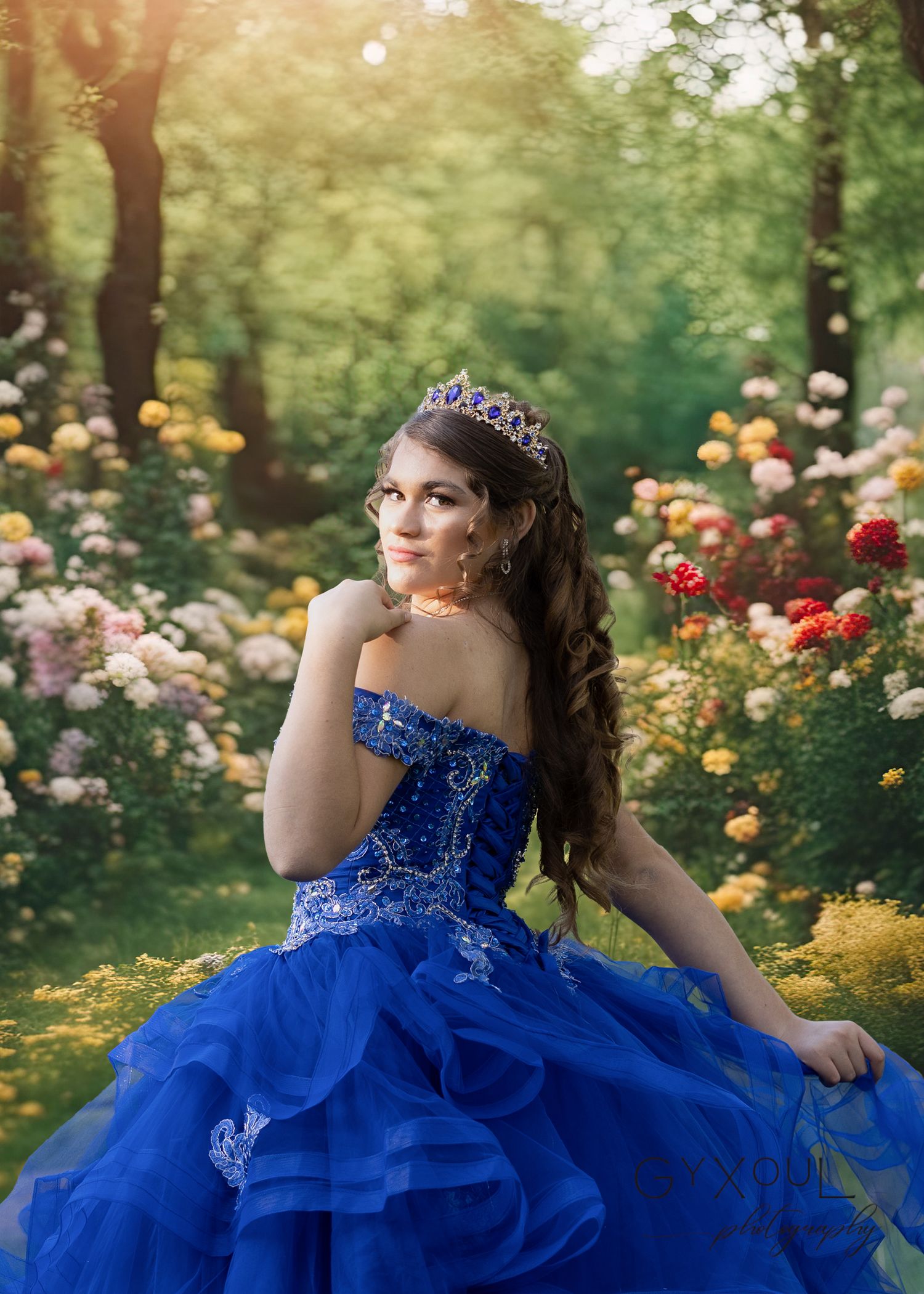 Enchanting royal blue gown with crystal embellishments photographed in a garden of blooming roses.