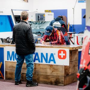 Customers at a Montana ski tuning service counter inside a winter sports equipment shop.