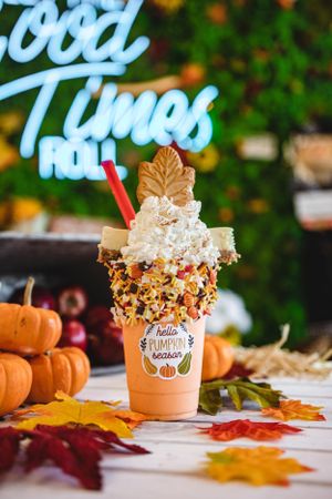 Hello Pumpkin Season freakshake topped with whipped cream, leaf cookie, and caramel popcorn rim with fall foliage decor.