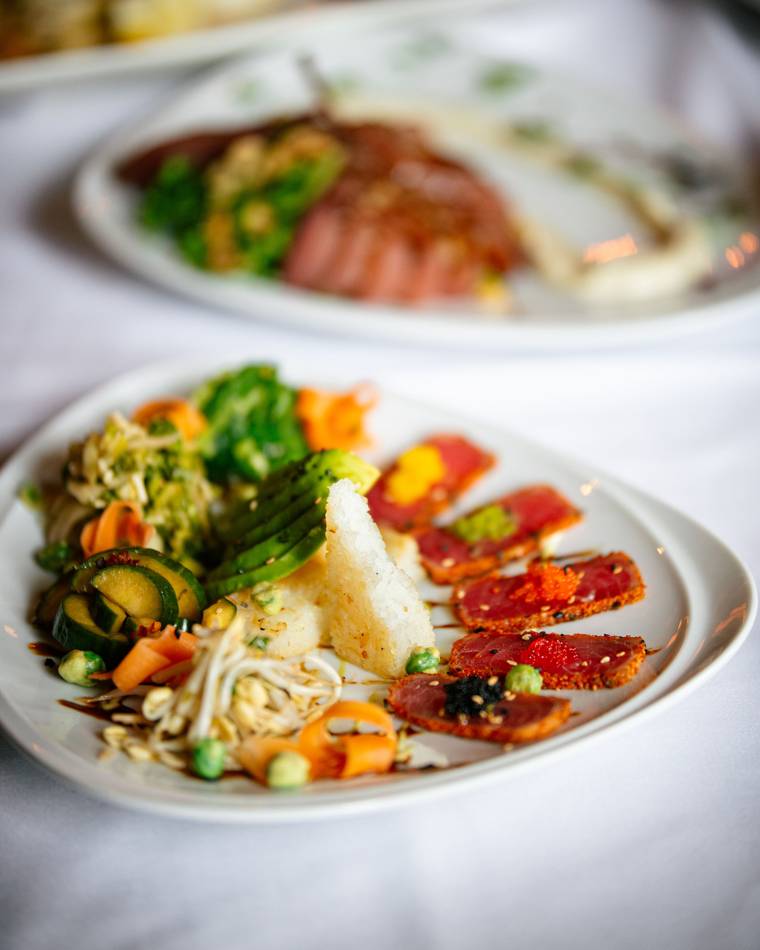 Colorful plate of seared tuna, mashed potatoes, mixed vegetables, and sprouts.