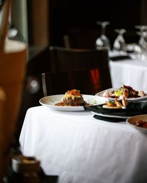 Upscale restaurant table setting with plated gourmet dishes on white linen tablecloth.