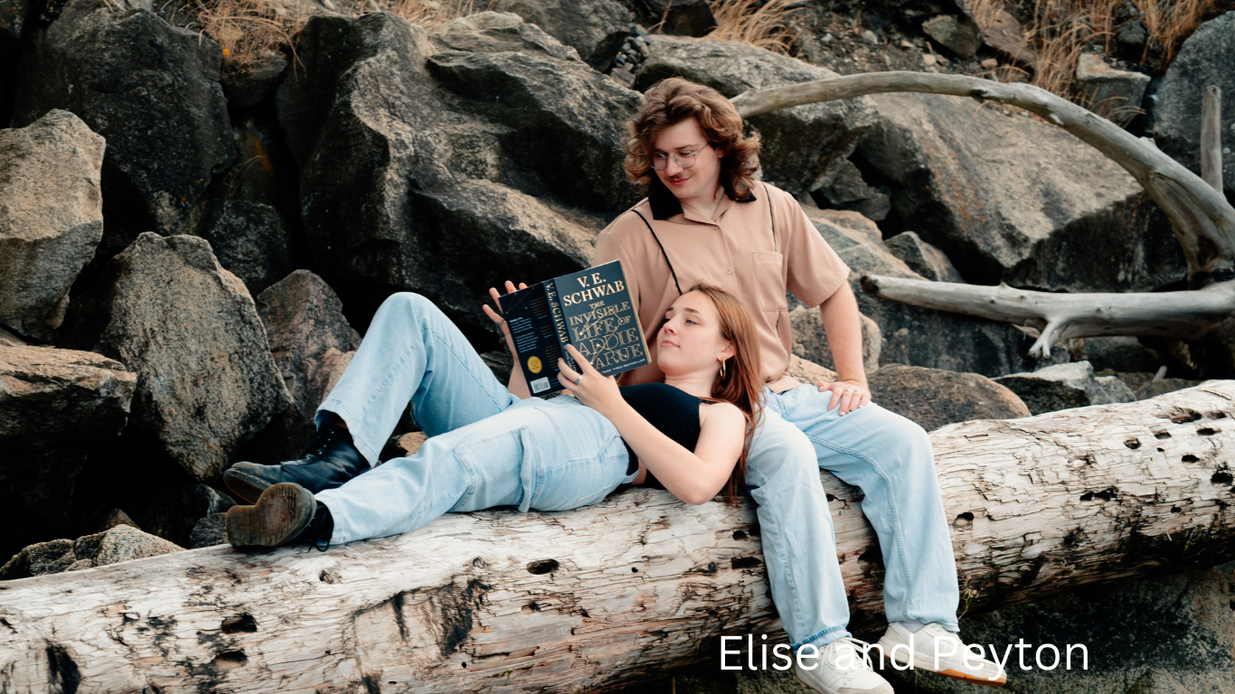 Two people relaxing on rocky beach while reading together.