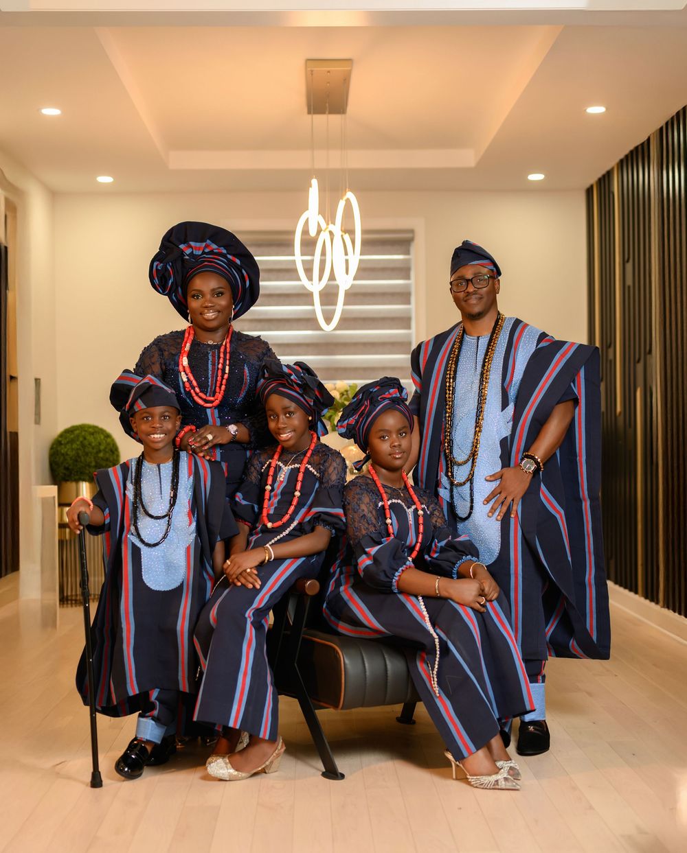 Group wearing matching blue and red striped traditional graduation attire pose together in an elegant hallway.