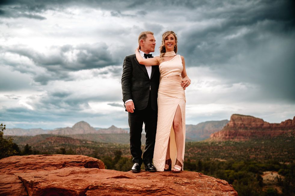 Formal portrait on red rock overlook with sweeping Sedona valley views.