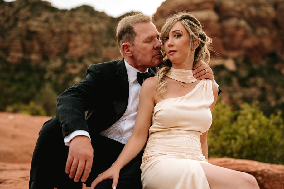 Romantic portrait session on Sedona red rocks with mountain vista in background.