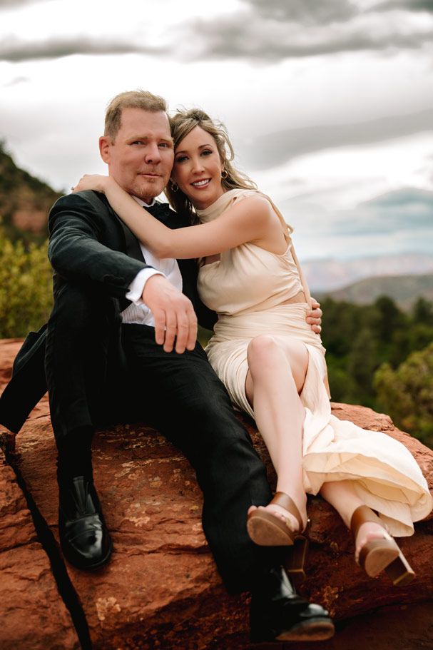 Intimate moment shared on Sedona red rocks with dramatic cloudy sky background.