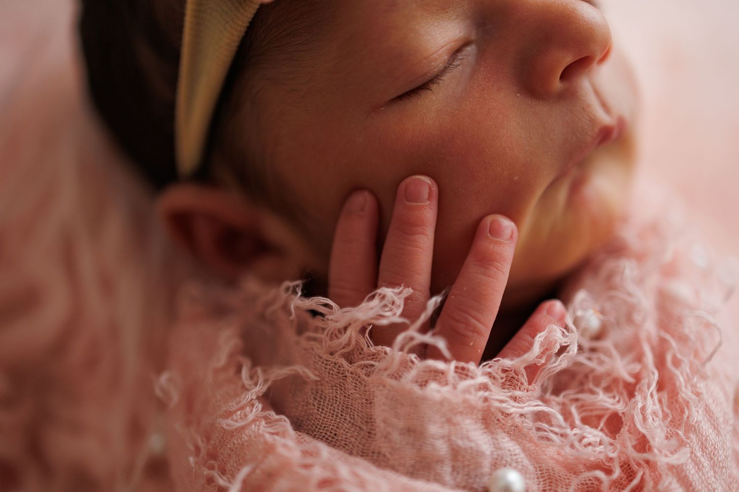 Soft pink tulle fabric creates a delicate backdrop for a newborn photography session.