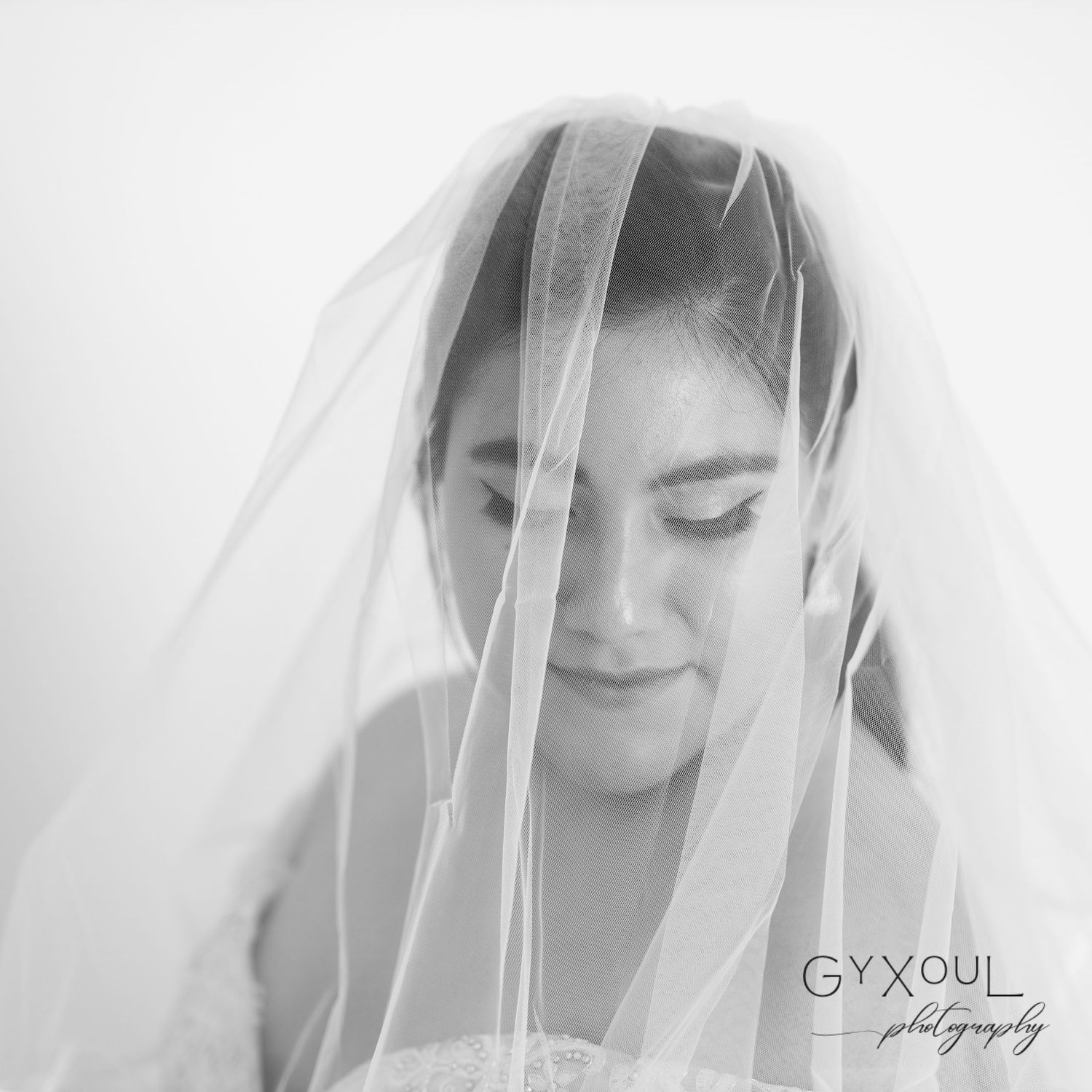 Ethereal bridal portrait with soft veil in black and white.