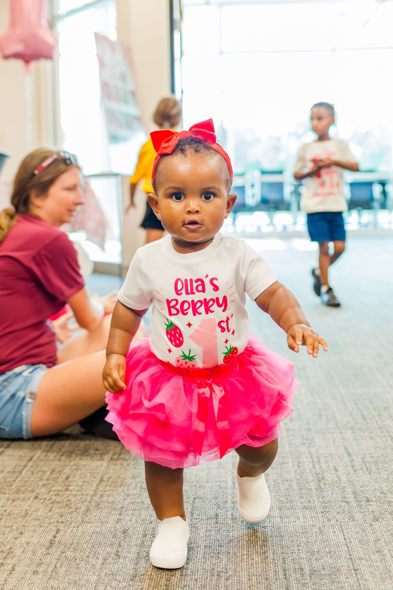 First birthday party celebration with pink tutu and strawberry-themed decorations.