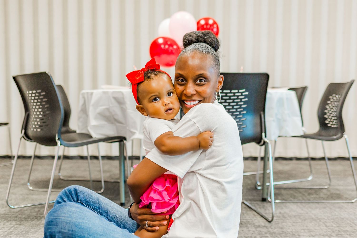 A tender moment between parent and child sitting in chairs against a striped wall.