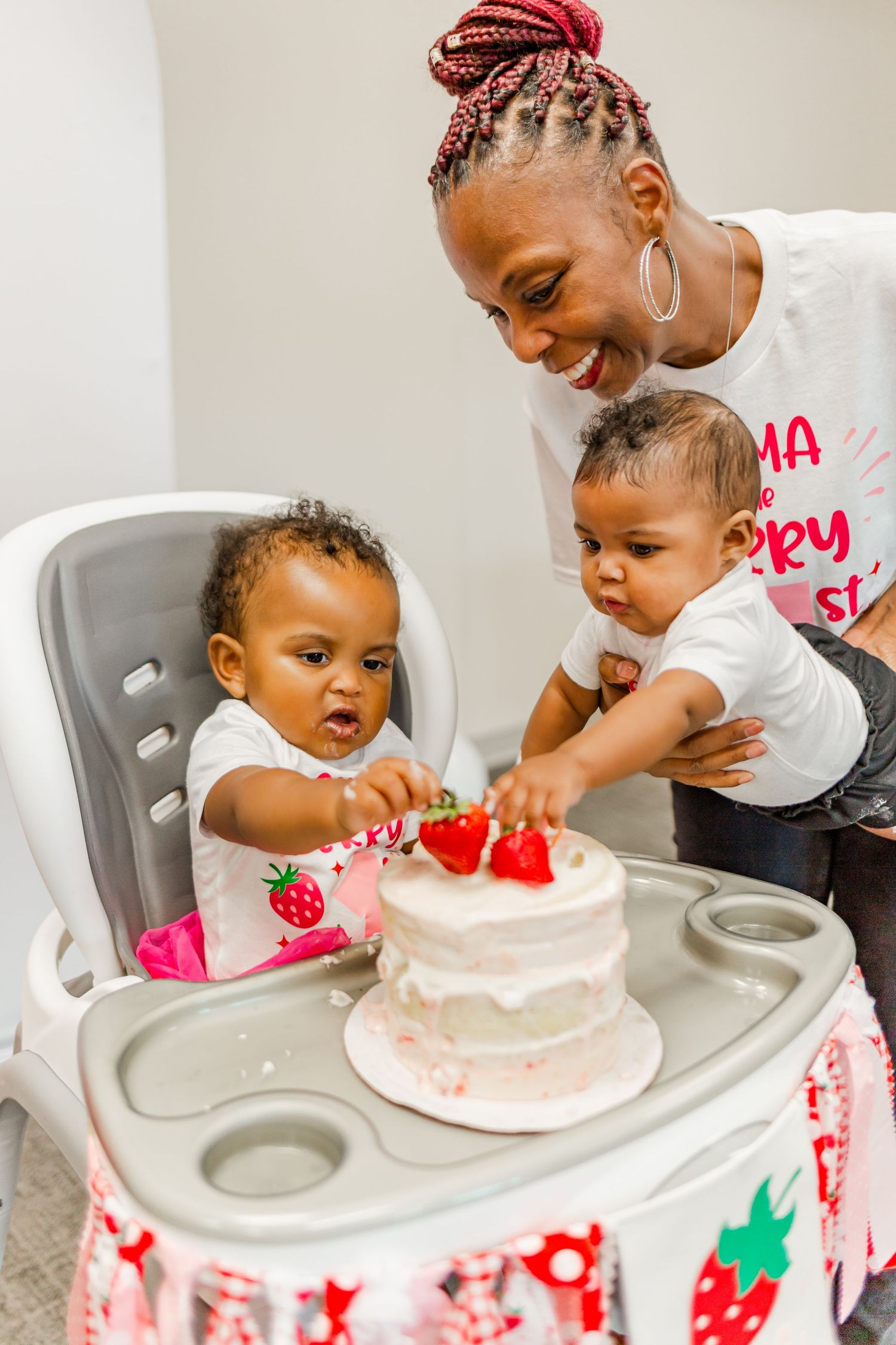 A joyful moment as small hands reach to touch a birthday cake on a decorated high chair tray.