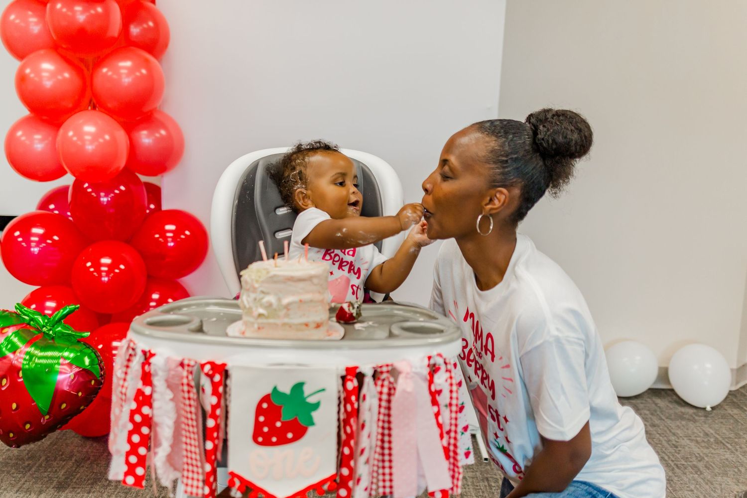 A celebratory moment with red balloon decorations and a strawberry-themed party setup.