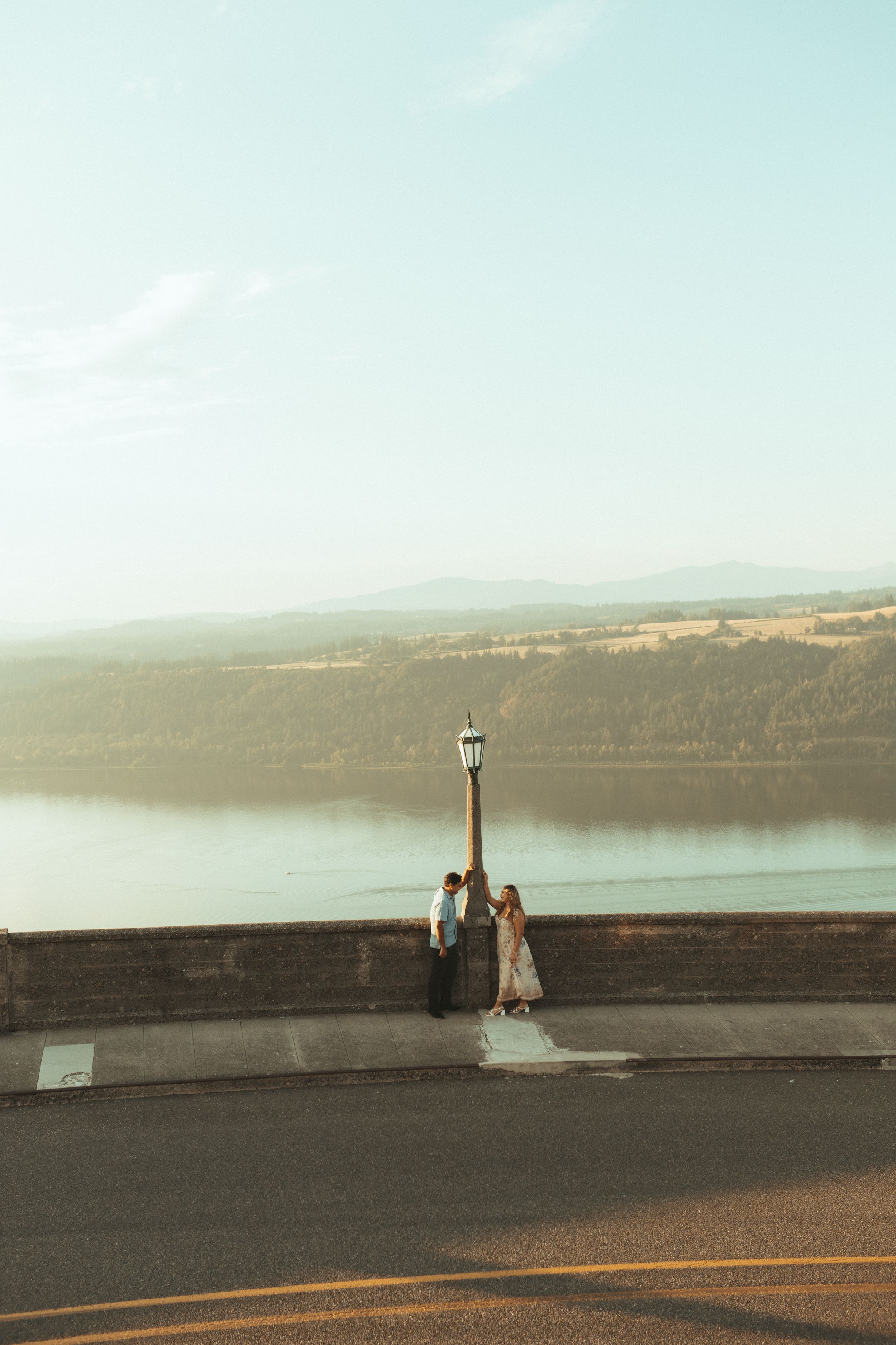 Panoramic sequence showing a person doing yoga poses on a stone wall overlooking a scenic lake at sunset.