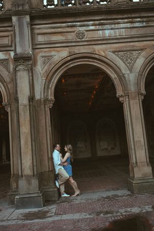 Couple embracing under ornate stone arches at Bethesda Terrace in Central Park, New York City.