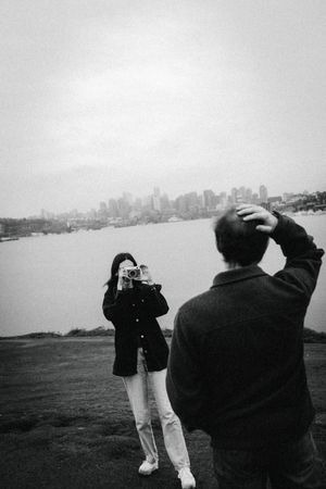 Black and white panoramic sequence showing people looking out at a distant city skyline across a body of water.