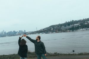 People walking along a waterfront path with scenic views of Lake Washington and Seattle skyline in the background.